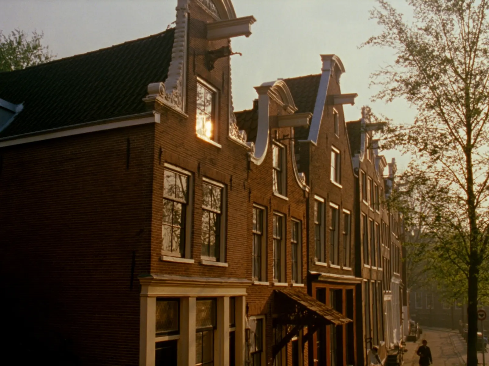 Gevels van Amsterdamse grachtenpanden in warm ochtendlicht